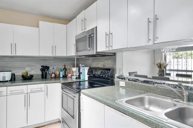 a kitchen with granite countertop a sink white cabinets and white appliances
