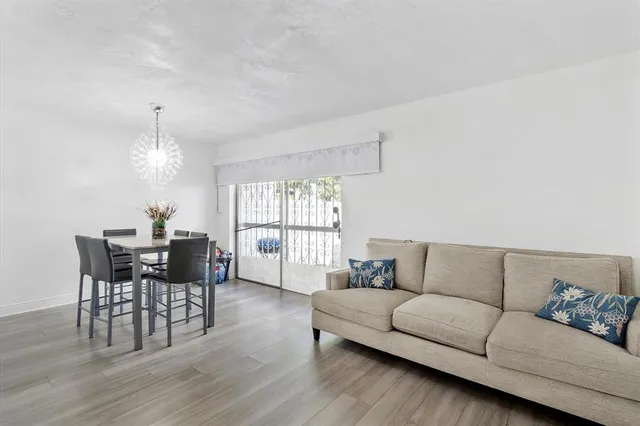 a living room with furniture and a dining table with wooden floor