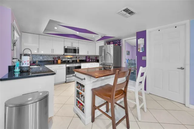 a kitchen with stainless steel appliances kitchen island granite countertop a refrigerator and a stove top oven