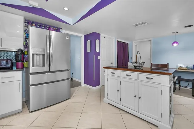 a kitchen with granite countertop a refrigerator and white cabinets