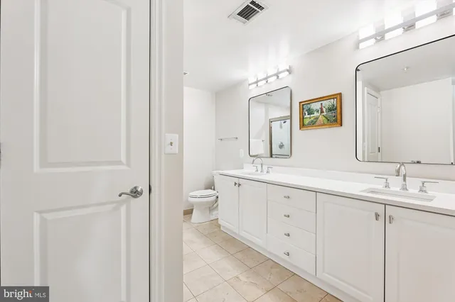 a spacious bathroom with a double vanity sink a mirror and a toilet