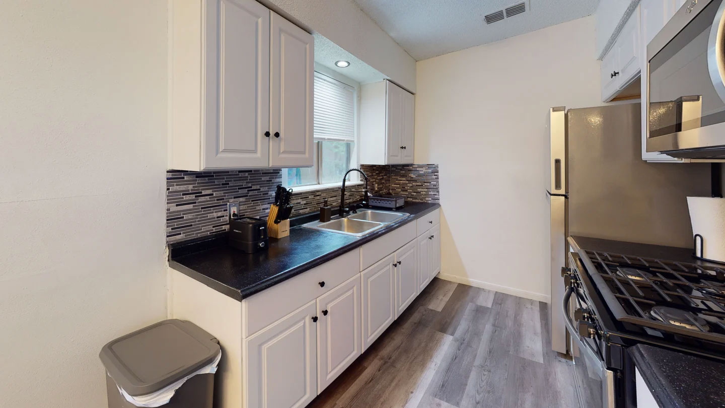 1109 Gardner Cove Austin, TX 78721 - Photo 6 of 13 A galley kitchen with sleek countertops and stainless steel appliances.