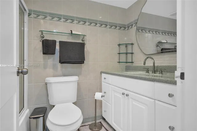 a bathroom with a granite countertop toilet sink and mirror
