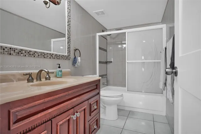 a bathroom with a granite countertop sink a toilet and shower
