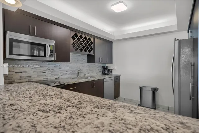 a kitchen with stainless steel appliances granite countertop a refrigerator and a stove top oven