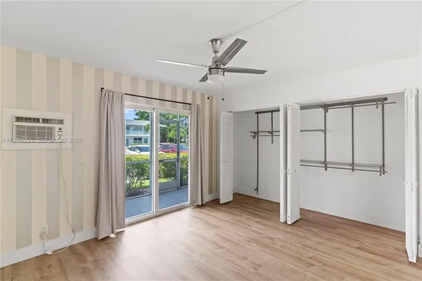 a view of a livingroom with wooden floor a ceiling fan and windows