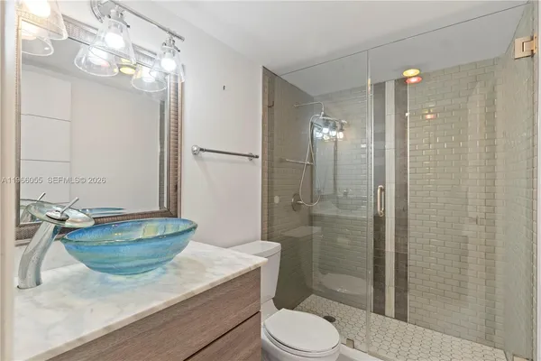 a bathroom with a granite countertop sink a toilet a mirror and shower