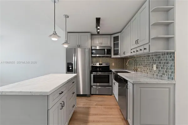 a kitchen with stainless steel appliances kitchen island a refrigerator sink and cabinets