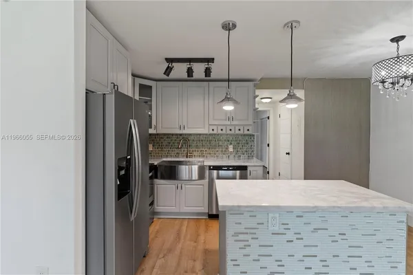 a kitchen with stainless steel appliances a refrigerator a sink and wooden floor