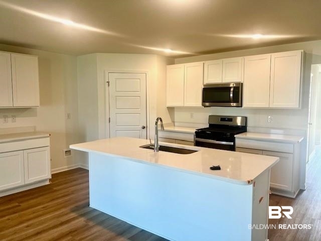 32063 Lyon Road Daphne, AL 36527 - Photo 2 of 4 Kitchen with white cabinets, a center island with sink, appliances with stainless steel finishes, and dark hardwood / wood-style flooring
