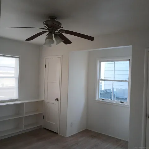an empty room with windows and fan
