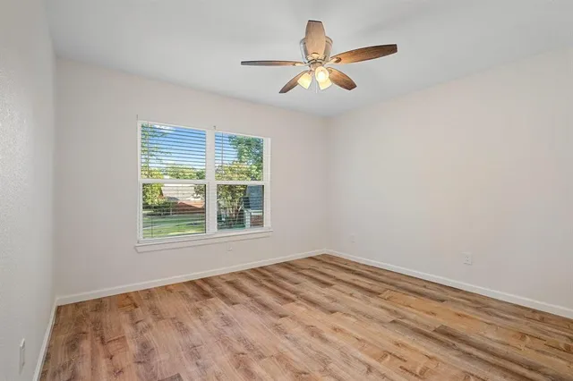 an empty room with a window and ceiling fan