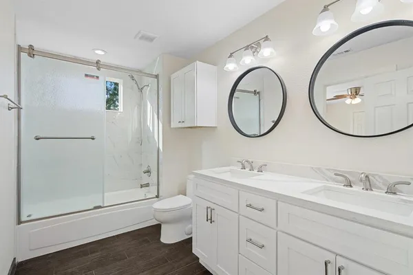 a bathroom with a granite countertop toilet a sink and a mirror