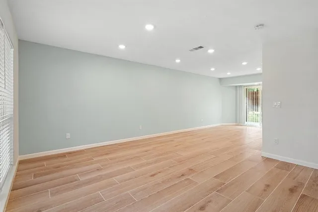 an empty room with wooden floor and natural light