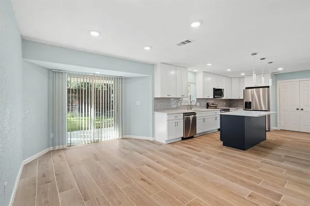 a large kitchen with a large counter top a sink stainless steel appliances and cabinets