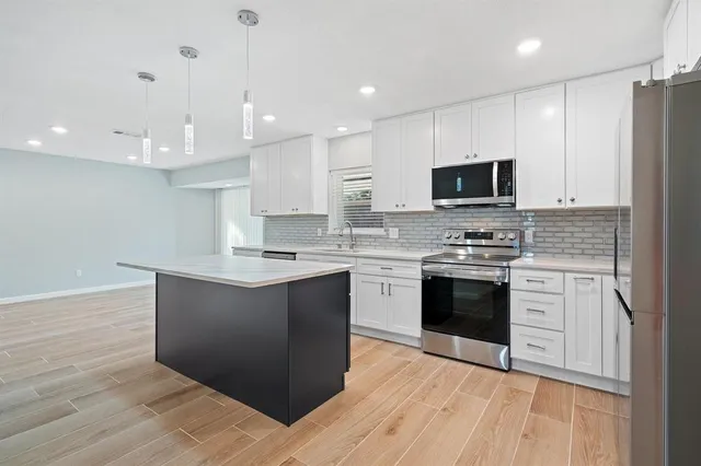 a kitchen with stainless steel appliances kitchen island granite countertop a stove a sink and a microwave
