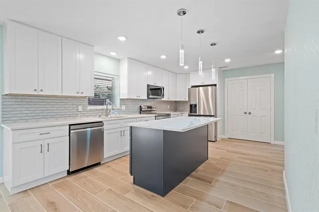 a kitchen with kitchen island granite countertop appliances cabinets and a sink