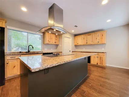 a kitchen with stainless steel appliances granite countertop a sink a stove and a wooden cabinets