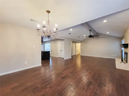 a view of an empty room with wooden floor and a chandelier