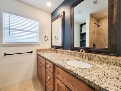 a bathroom with a granite countertop sink and a large mirror