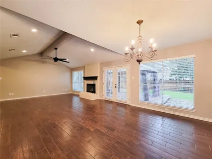 a view of a big room with wooden floor a chandelier and windows