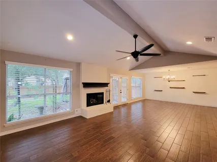 an empty room with wooden floor fireplace and windows