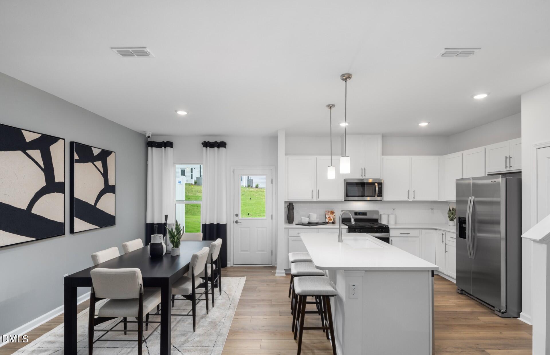 1118 Carpenter Falls Avenue Durham, NC 27704 - Photo 4 of 18 a kitchen with stainless steel appliances kitchen island a table chairs and a refrigerator