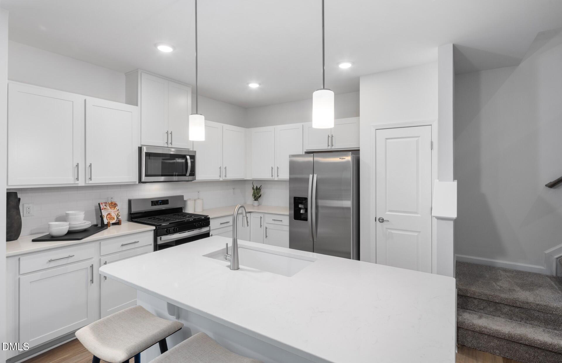 1118 Carpenter Falls Avenue Durham, NC 27704 - Photo 5 of 18 a kitchen with stainless steel appliances a refrigerator stove microwave and white cabinets