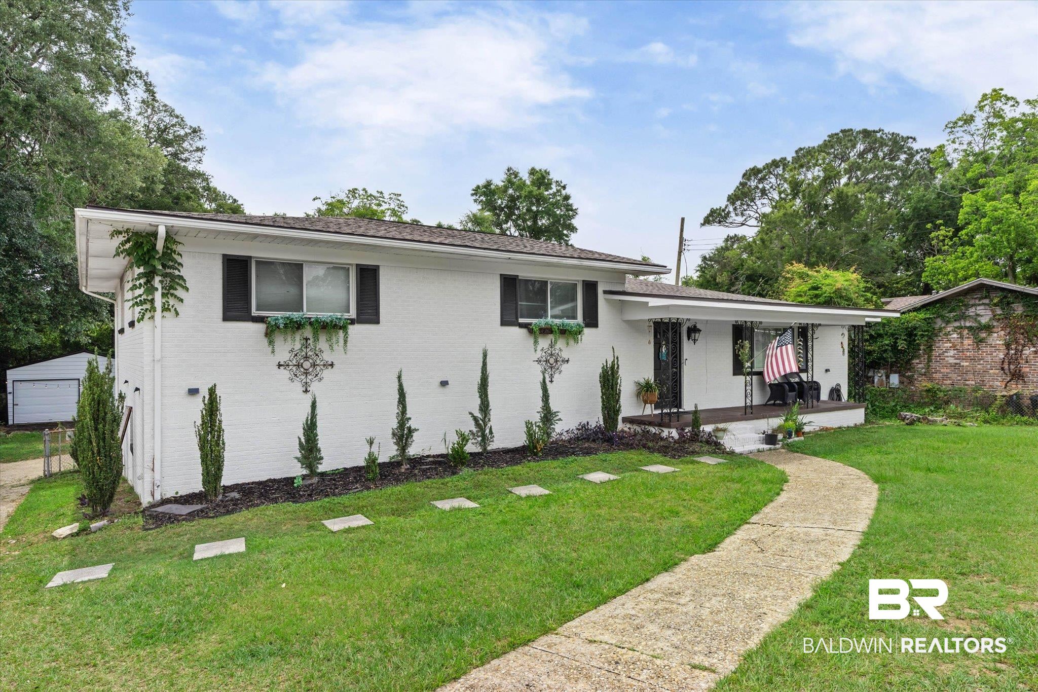 4213 Shan Drive East Mobile, AL 36693 - Photo 28 of 35 White brick exterior with dark shutters, a covered entry porch, a paved walkway, and a manicured lawn