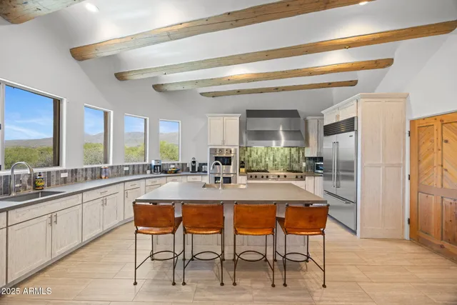 a kitchen with stainless steel appliances granite countertop a refrigerator a stove and a sink with wooden floors