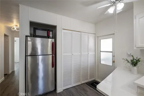 a view of a refrigerator in kitchen and an empty room with wooden floor