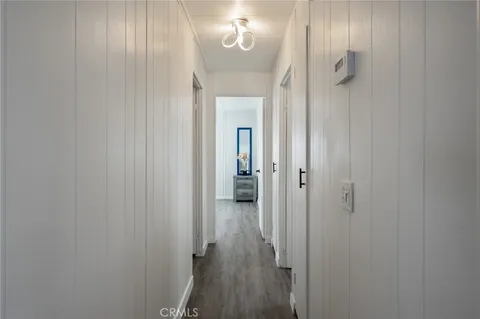 a view of a hallway with wooden floor and a bathroom