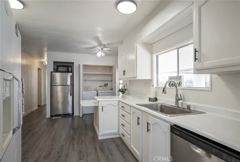 a kitchen with a sink stainless steel appliances cabinets and a window