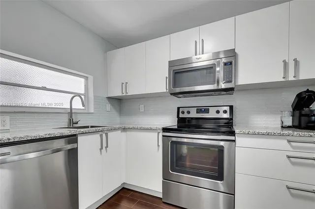 a kitchen with granite countertop white cabinets and stainless steel appliances