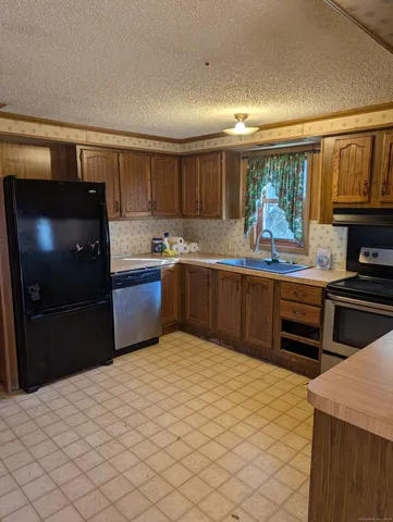 a kitchen with stainless steel appliances kitchen island granite countertop a refrigerator and a stove top oven