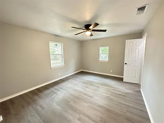 a view of empty room with wooden floor and fan