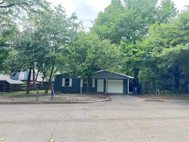 a front view of a house with a garden and trees