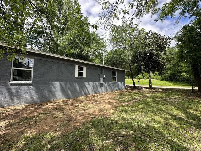 a backyard of a house with large trees and parked