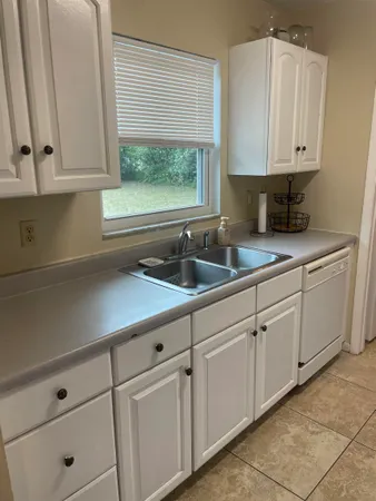 a kitchen with white cabinets and a window