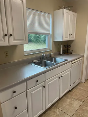 a kitchen with white cabinets and a window