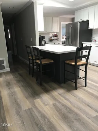 a dining hall with stainless steel appliances a sink dishwasher a stove a refrigerator with a dining table and chairs