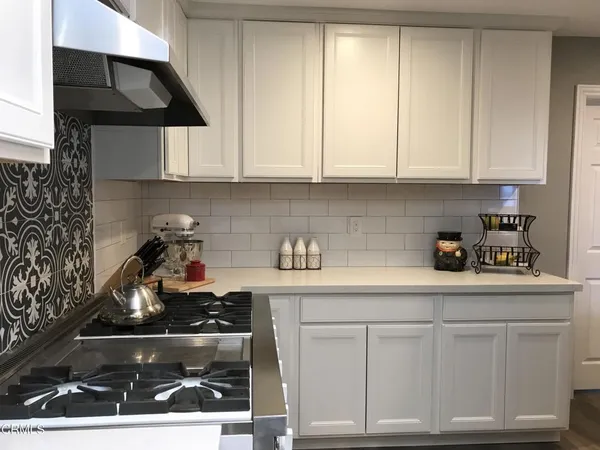 a kitchen with white cabinets and appliances