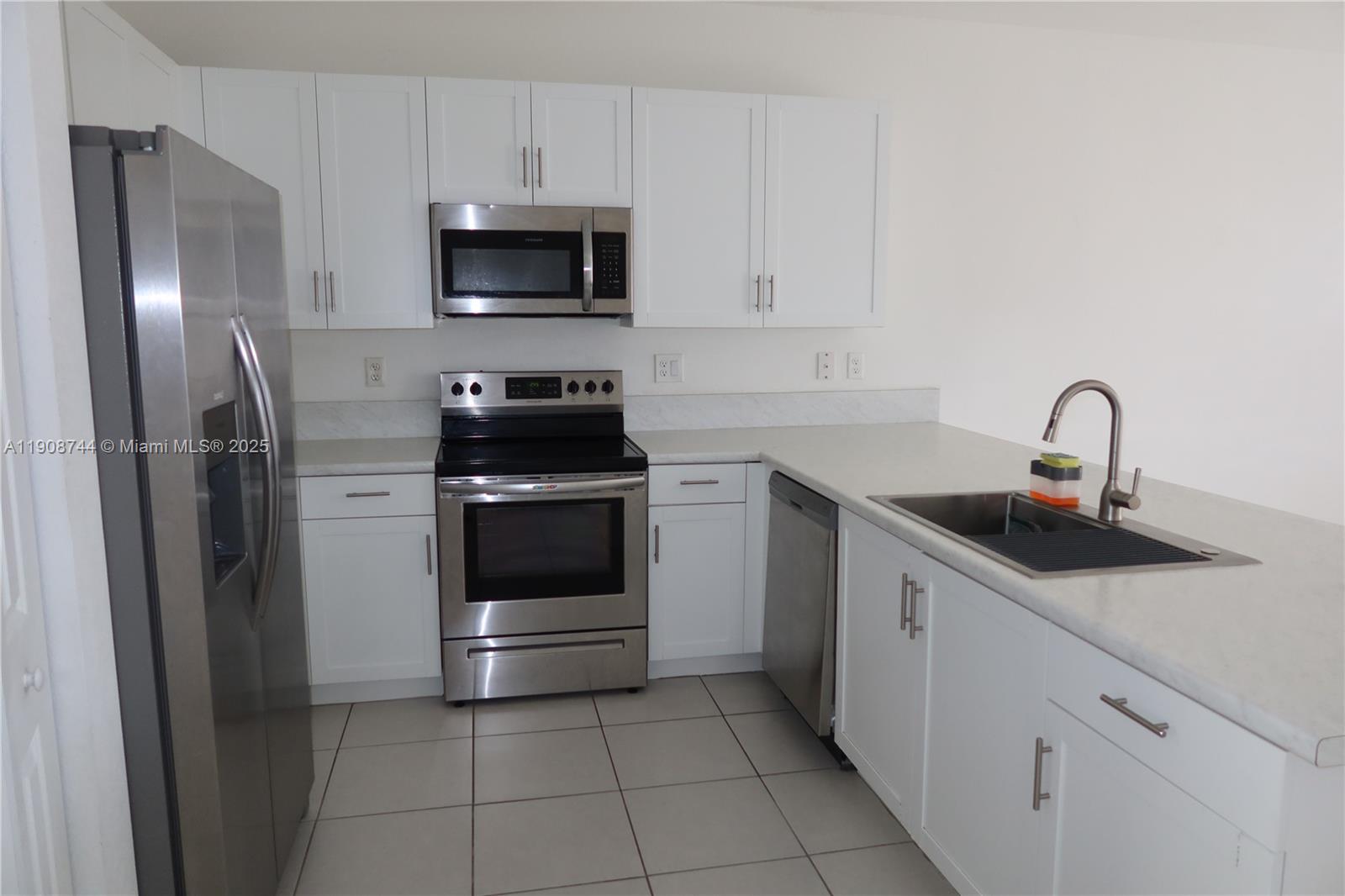 18240 Southwest 148th Road, Unit 18240 Miami, FL 33187 - Photo 4 of 30 a kitchen with a sink and stainless steel appliances