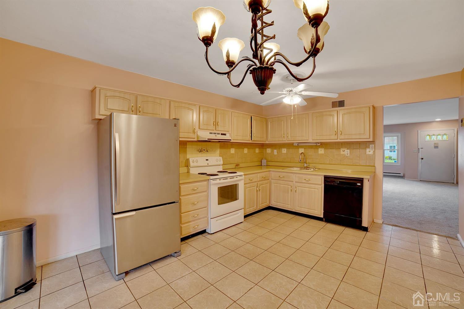 136 Rigi Strasse, Unit E Freehold, NJ 07728 - Photo 13 of 30 a white kitchen with a refrigerator a stove top oven a sink and dishwasher