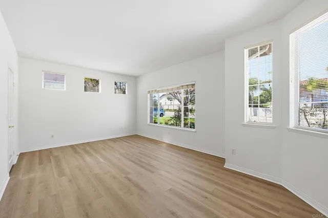 a view of an empty room with wooden floor and windows