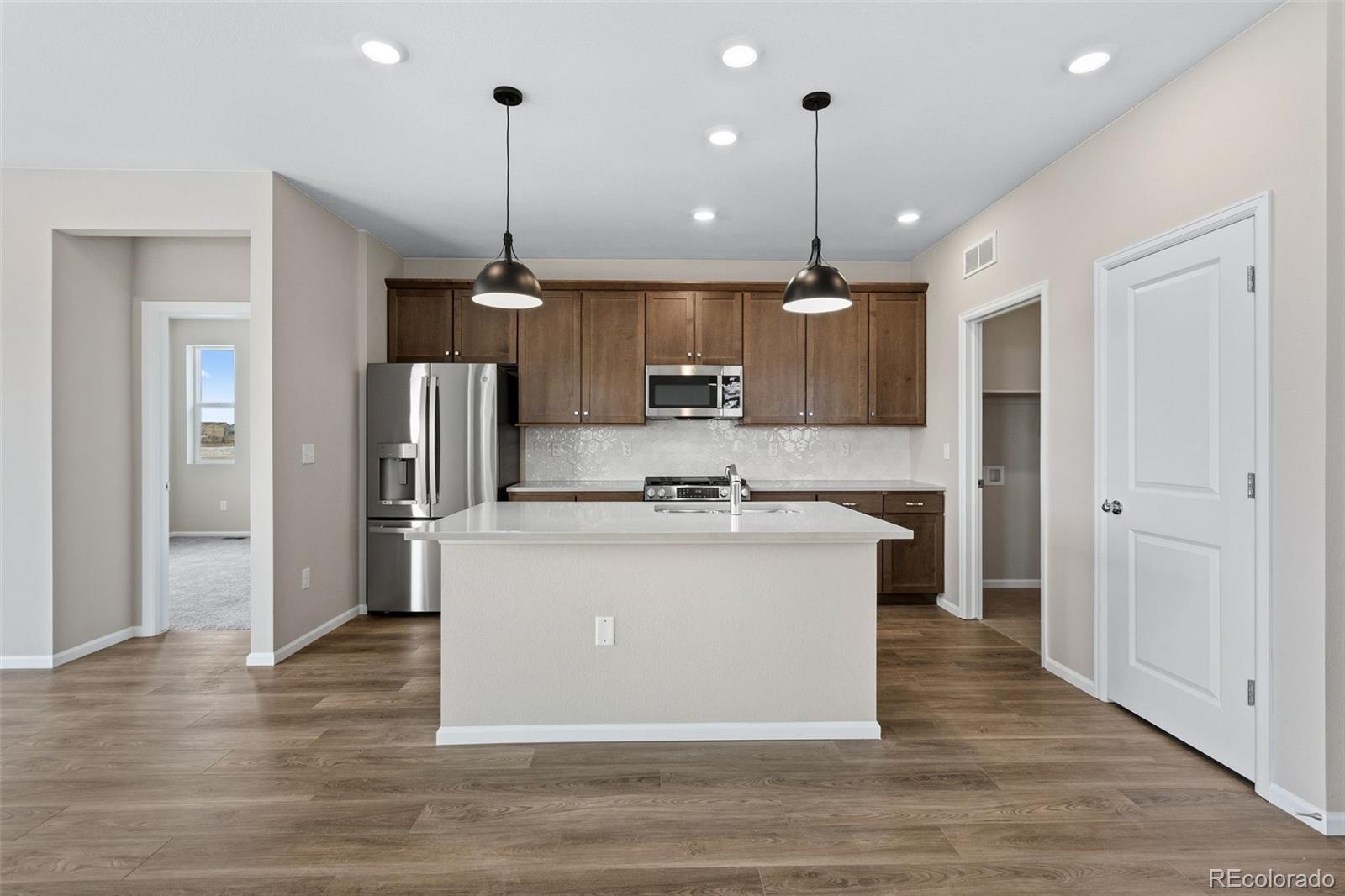 6028 Keyser Place Brighton, CO 80601 - Photo 2 of 26 a kitchen with stainless steel appliances granite countertop a refrigerator a stove a sink and a wooden floors