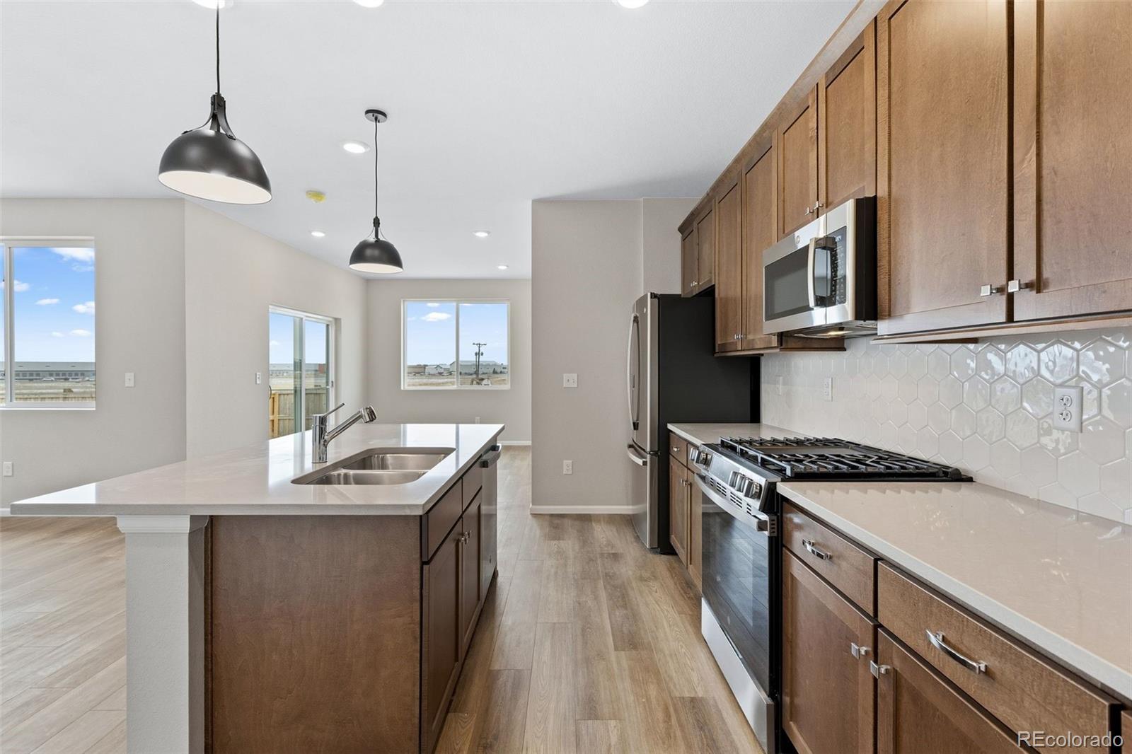 6028 Keyser Place Brighton, CO 80601 - Photo 4 of 26 a kitchen with stainless steel appliances granite countertop a sink a stove and a wooden floors
