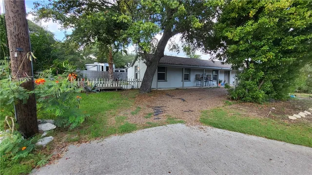 a front view of a house with a garden and trees