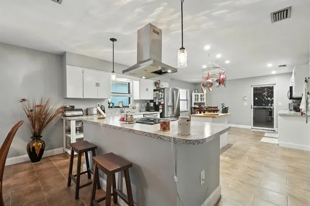 a kitchen with stainless steel appliances kitchen island granite countertop a sink and refrigerator