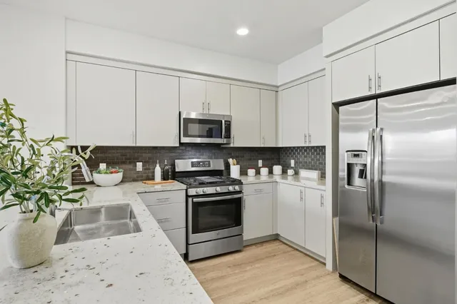 a kitchen with stainless steel appliances kitchen island granite countertop a refrigerator a stove and a sink